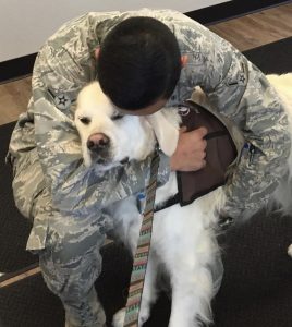 Airman hugging white therapy dog. 